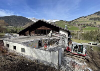 Travaux de démolition du Chalet le Clos des Pierres à Rougemont, avec une pelleteuse sur le chantier, en cadre alpin.