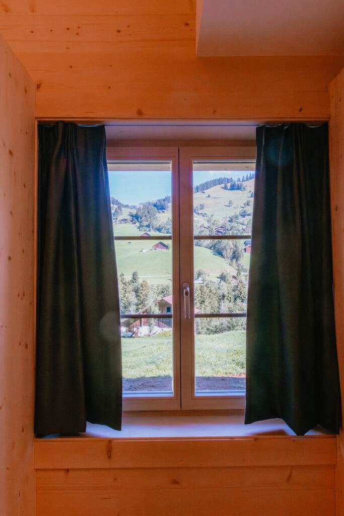 Vue d'un paysage alpin à travers une fenêtre de chambre bordée de rideau